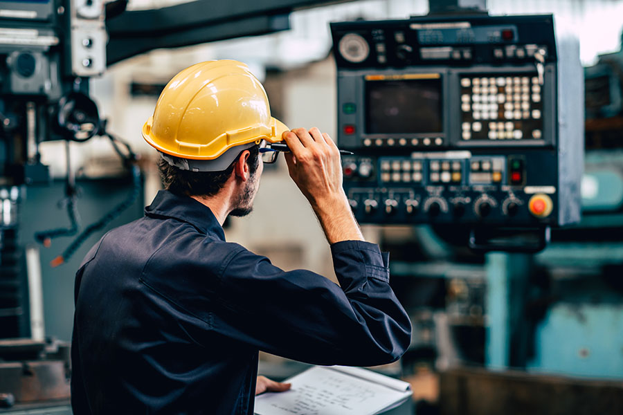 Specialized Business Insurance - Worker in Hard Hat Checks Equipment In A Manufacturing Plant